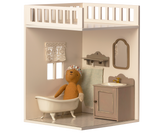 A minimalist dollhouse bathroom with two small windows and curtains, featuring a decorated tiled floor.
