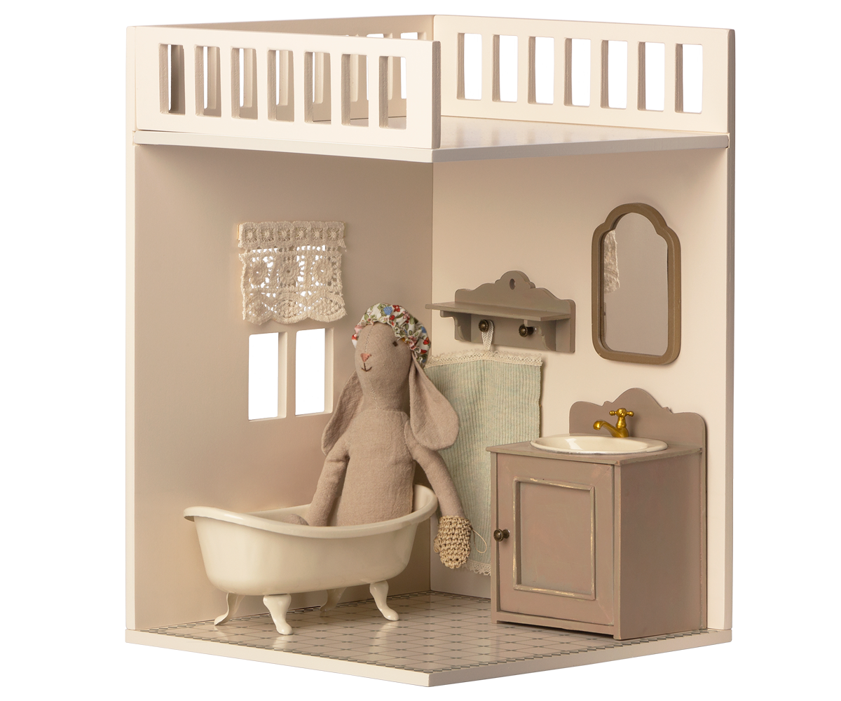 A minimalist dollhouse bathroom with two small windows and curtains, featuring a decorated tiled floor.