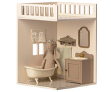 A minimalist dollhouse bathroom with two small windows and curtains, featuring a decorated tiled floor.
