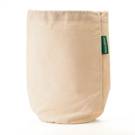 Huckleberry Hideaway natural canvas cotton storage bag with green brand label on white background.