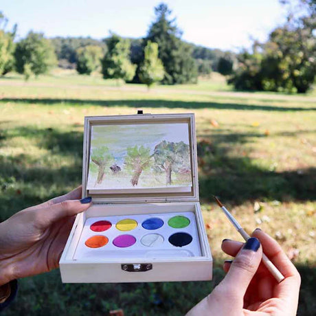 Huckleberry landscape paint kit used outdoors with watercolor palette and brush.