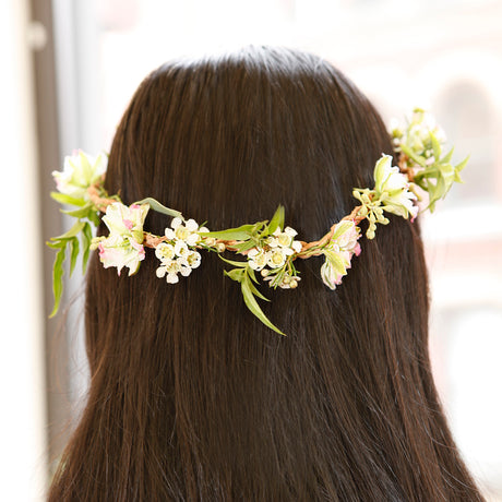 Back view of a person with long dark hair wearing a delicate DIY flower crown made of small white and pink blossoms.