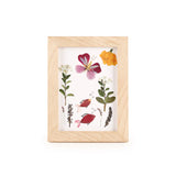 Huckleberry pressed flower art kit in natural wood frame with dried botanicals arranged as fish and butterfly.