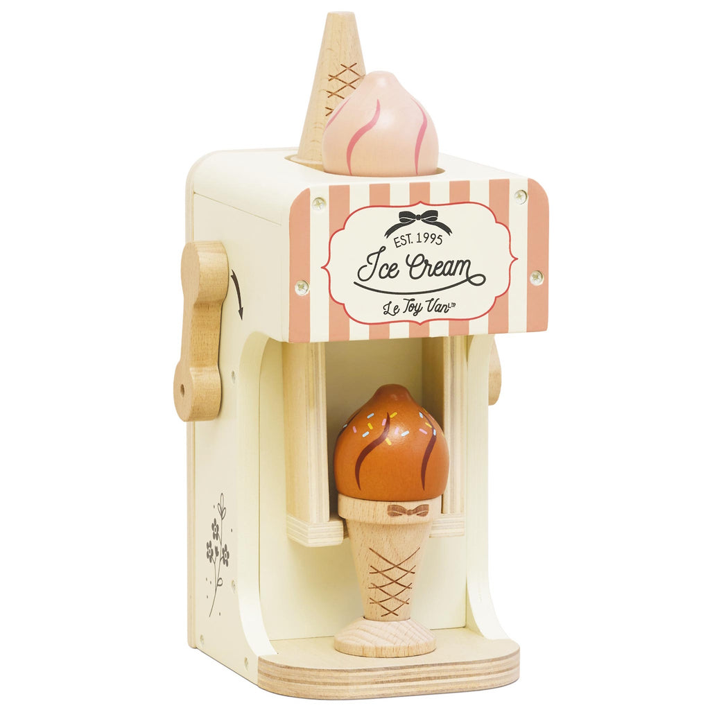 Wooden toy ice cream machine with a pink and white striped design. It features a cone with a scoop on top and an ice cream cone in the opening below.