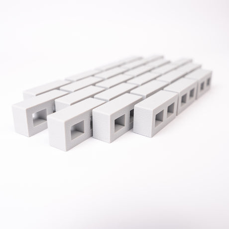 A close-up of rows of small, rectangular, gray blocks with square openings, aligned diagonally on a white background, creating a minimalistic pattern.