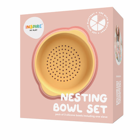 Packaging for Inspire My Play's Nesting Bowl Set, featuring a yellow and coral silicone bowl with a sieve design. Soft pink background, playful, child-friendly tone.