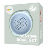 Packaging for a "Nesting Bowl Set" with a cute, pastel blue silicone sieve visible. Labeled for use with play products, the design is playful and modern.