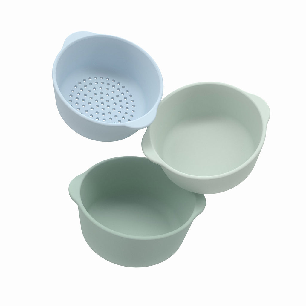 Three pastel-colored kitchen bowls, including a blue colander, a light green, and a pale mint bowl, are arranged on a white background.