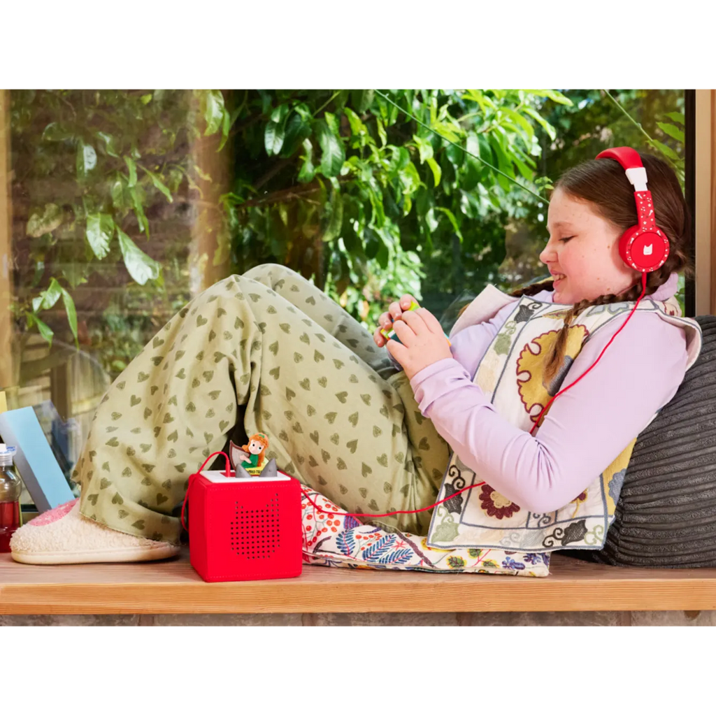 A playful girl with orange hair and a green dress plays a harp beside a book titled "WORLD TALES" audiobook.