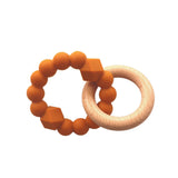 A stylish and practical teething toy featuring a soft honey-coloured silicone ring with beaded and geometric textures, paired with a smooth wooden ring.