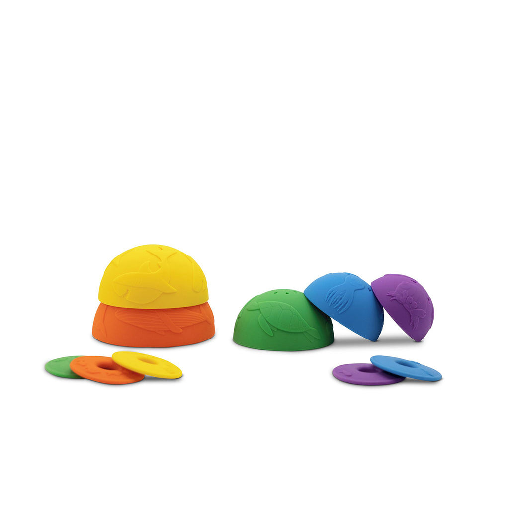 A playful set of ocean-themed stacking cups, fully unstacked and arranged in two groups, showcasing their embossed sea creature designs, with matching discs placed nearby.