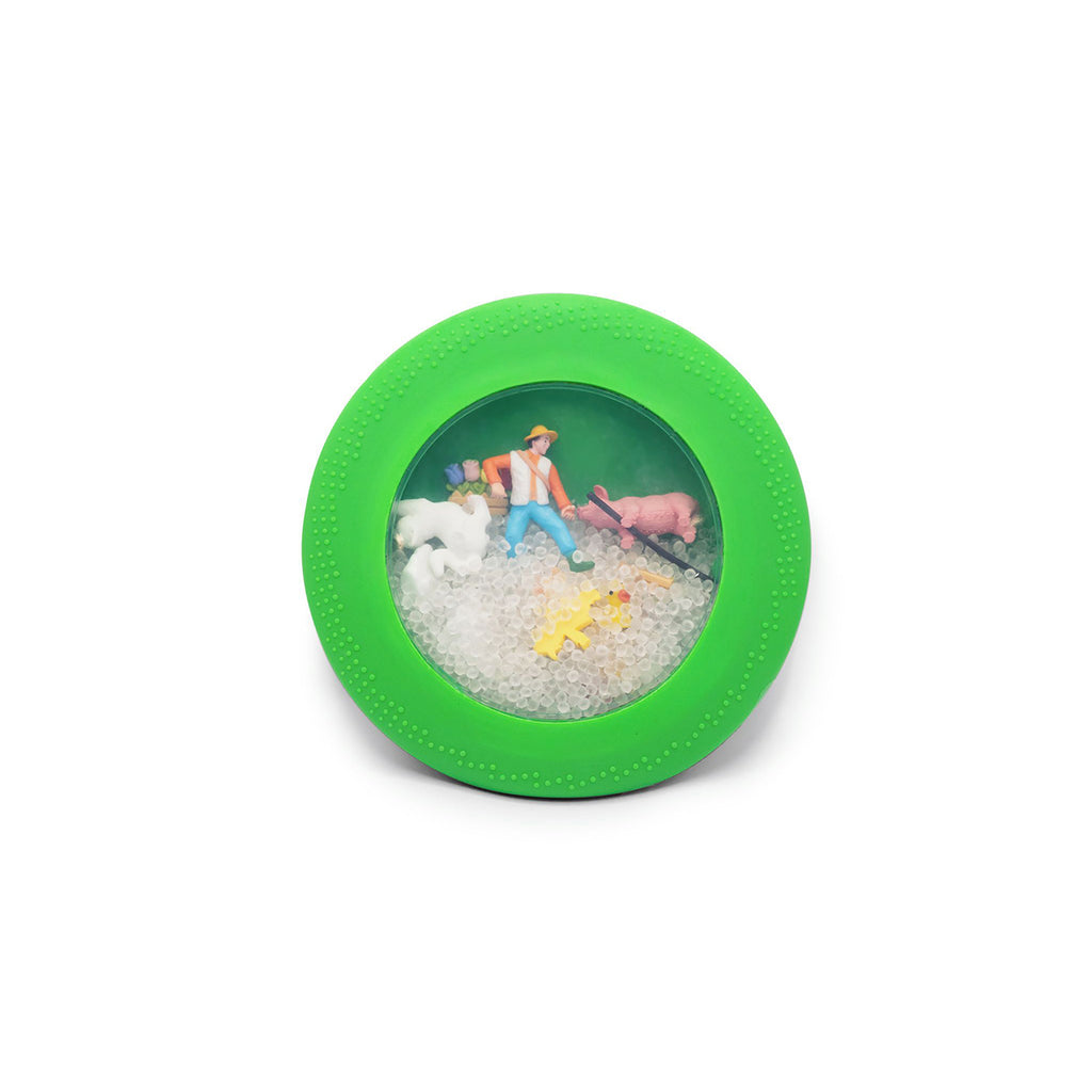 A close-up of the green peekaboo bag showing a miniature farm scene inside with tiny farm animal figures.