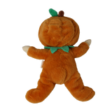 Back view of a plush doll in an orange pumpkin suit with a green leaf and stem on its hood.