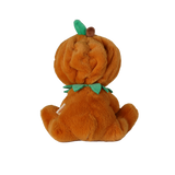 Back view of a seated plush doll in an orange pumpkin suit with a green leaf and stem on its hood.