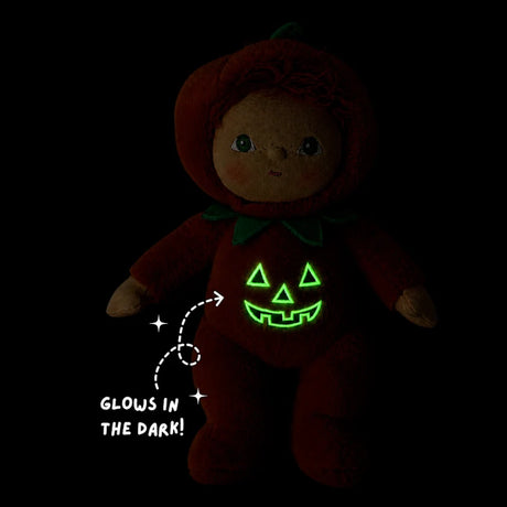 Plush doll in a dark room with a green glow-in-the-dark jack-o'-lantern face on its suit.