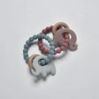 Blue and mauve silicone and wooden baby elephant teether toys arranged in a flat lay view.