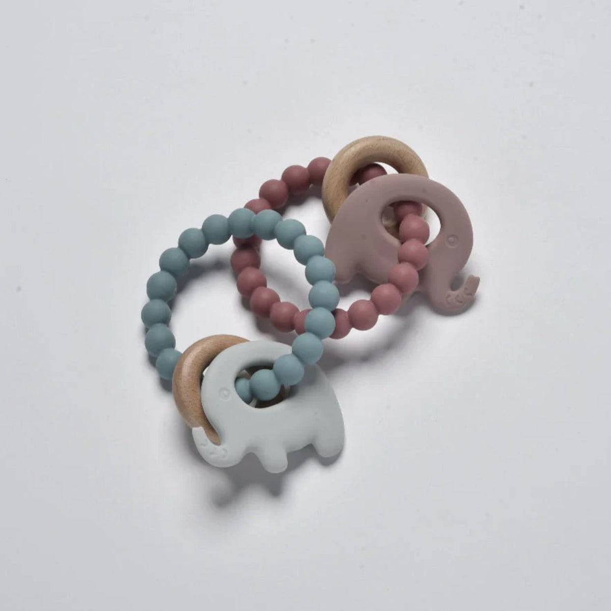 Blue and mauve silicone and wooden baby elephant teether toys arranged in a flat lay view.
