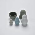 Four silicone nesting dolls in muted grey and blue tones shown partially unnested in a flat lay view.