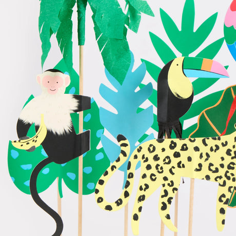 Paper-cut jungle animal cake toppers, including a monkey, toucan, and leopard, with tropical leaf decorations.