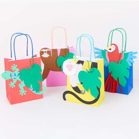 Four colorful jungle-themed gift bags featuring a lizard, sloth, monkey, and parrot with green leaf tags.