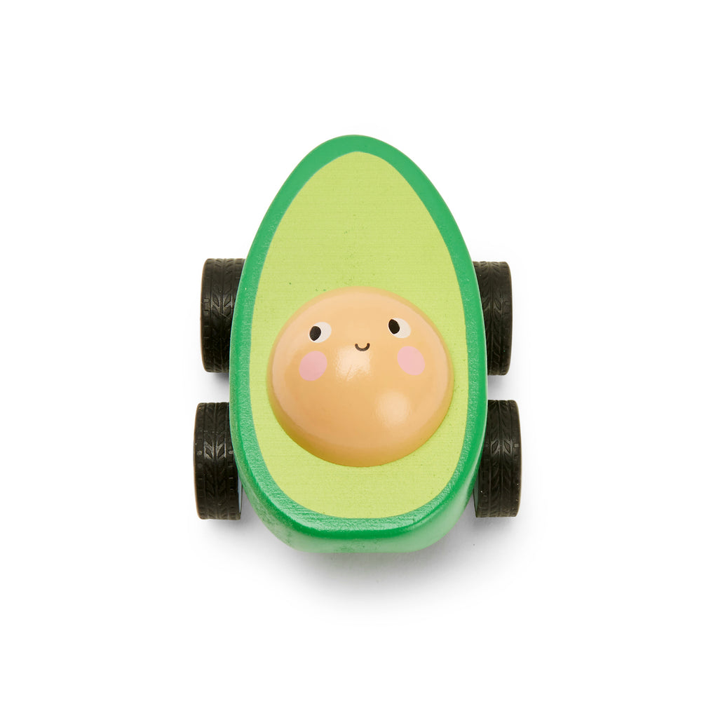 Toy car shaped like a cheerful avocado with a smiling pit face. The green body has four black wheels. Playful and whimsical tone.