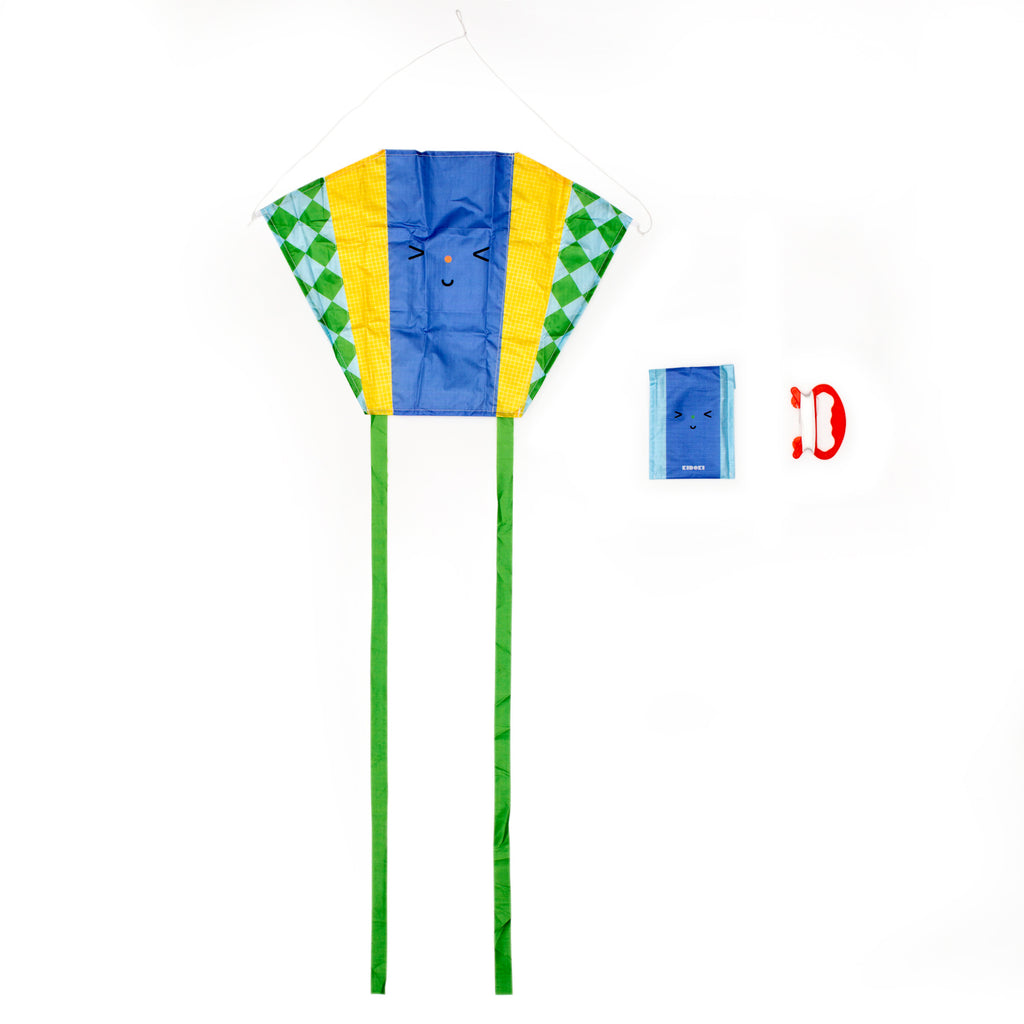 Vibrant kite with a blue and yellow face and green diamond-patterned sides. Features a smiling face and two long green tails. Includes red handle and packaging.