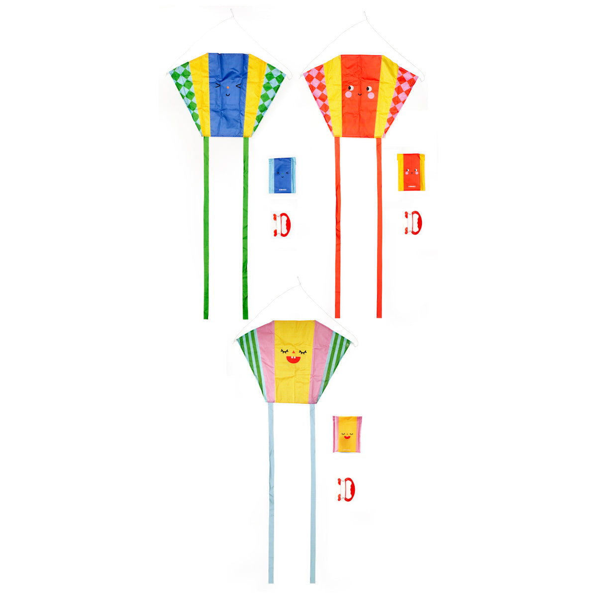Three colorful kites with smiling faces and long tails. Each kite has a matching carrying pouch and a red handle below them. Playful and cheerful vibe.