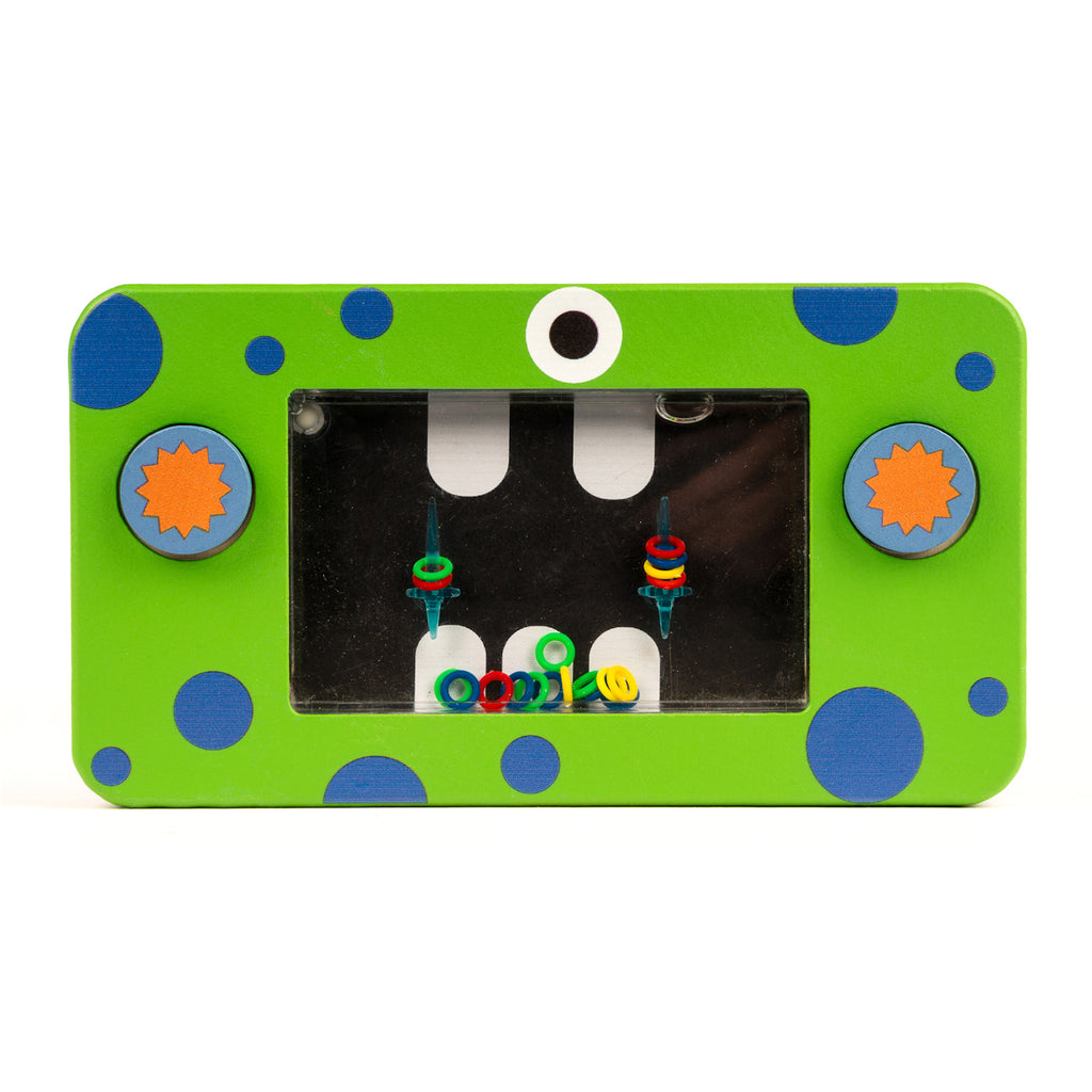 Bright green rectangular toy with blue polka dots and two gear-shaped knobs, featuring a black screen with colorful rings and a whimsical eye design.