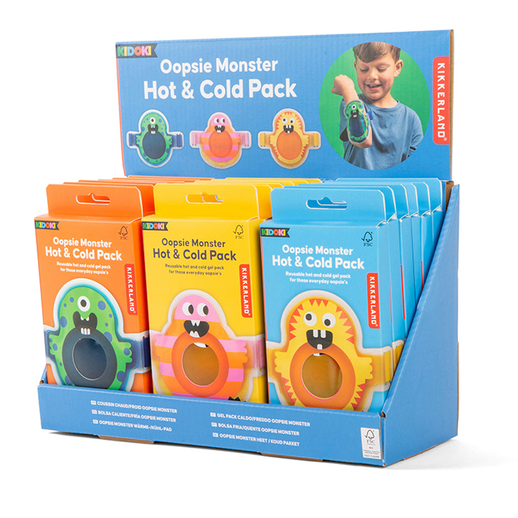 Display box of colorful "Oopsie Monster Hot & Cold Pack" packaging with playful monster designs. A smiling child uses one. Vibrant and fun theme.