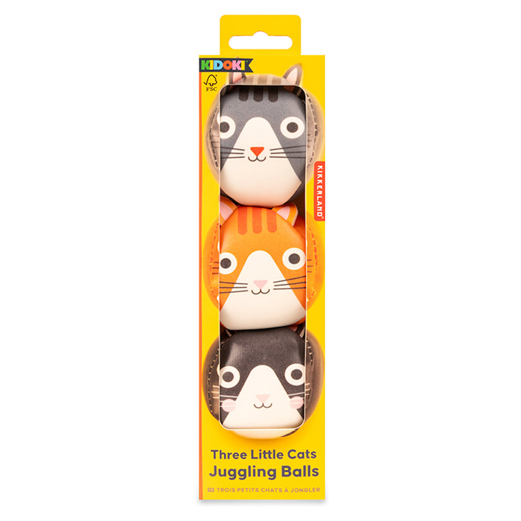 Yellow packaging shows three juggling balls with cute cat faces in gray, orange, and black. Text reads “Three Little Cats Juggling Balls.” Playful vibe.