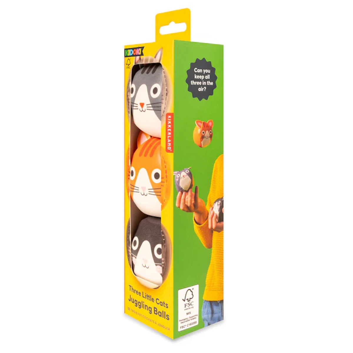 Yellow packaging shows three juggling balls with cute cat faces in gray, orange, and black. Text reads “Three Little Cats Juggling Balls.” Playful vibe.