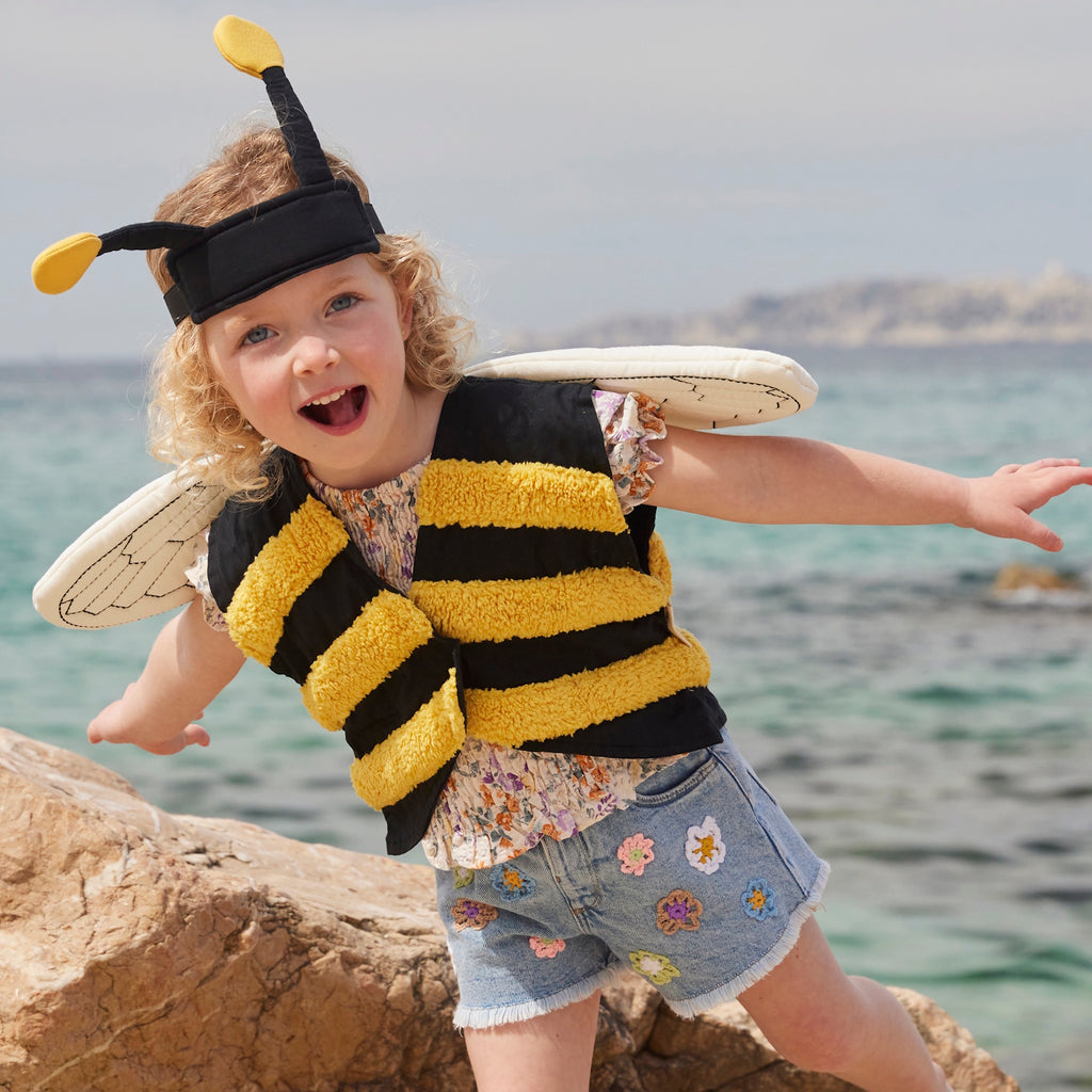 A playful bee costume for pets featuring yellow and black stripes, translucent wings with vein details, and a black headband with yellow pom antennas.