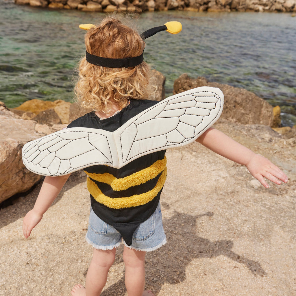 A playful bee costume for pets featuring yellow and black stripes, translucent wings with vein details, and a black headband with yellow pom antennas.