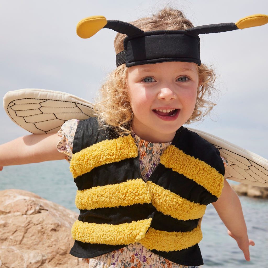 A playful bee costume for pets featuring yellow and black stripes, translucent wings with vein details, and a black headband with yellow pom antennas.