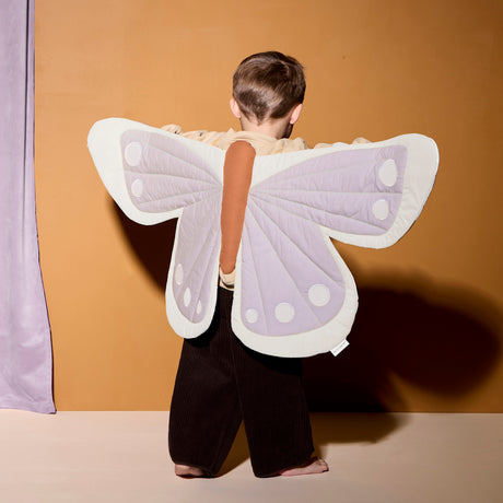 Child viewed from behind wearing soft purple and cream butterfly dress-up wings.