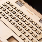Close-up of a wooden toy laptop with raised letter and number keys.