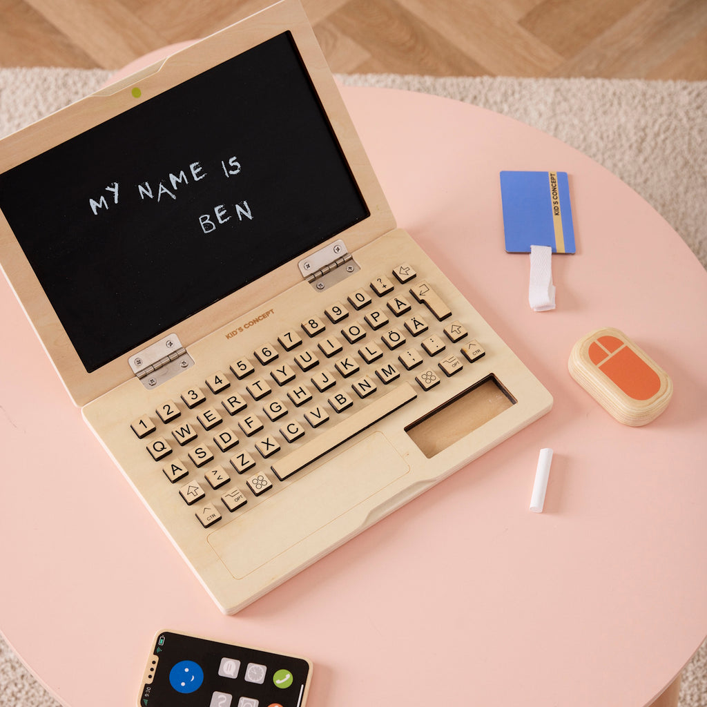 Wooden toy laptop set includes a laptop, smartphone, and mouse. The laptop has a black screen and keyboard. Playful and educational.
