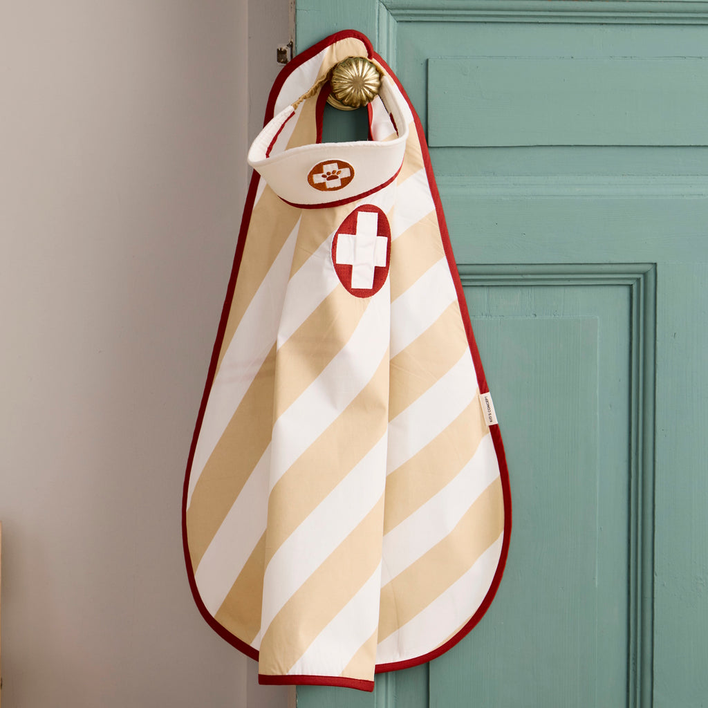 Children's doctor costume set with a striped apron and matching hat, both featuring a white cross on a red circle, includes two circular badges.