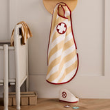 Striped doctor dress-up cape hanging on a wall hook next to a nurse cap on the floor.