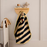 Striped firefighter dress-up cape with flame emblem hanging on a wall shelf peg in a kid's room.