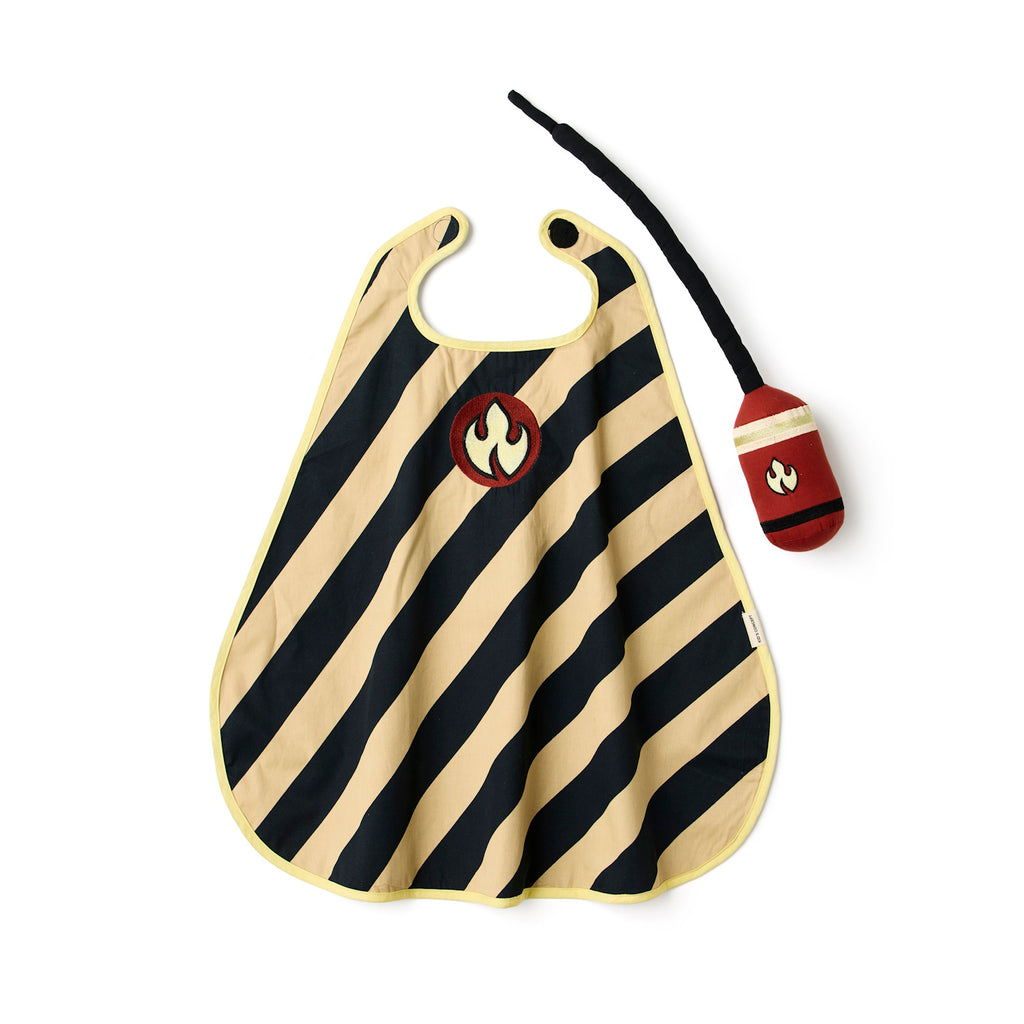 A tan and black striped cape with a flame emblem in a red circle on the chest. A matching red and black toy with a flame design is beside it.