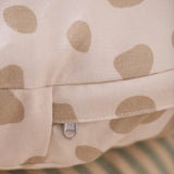 Close-up of a beige cushion with brown spots and a silver YKK zipper.
