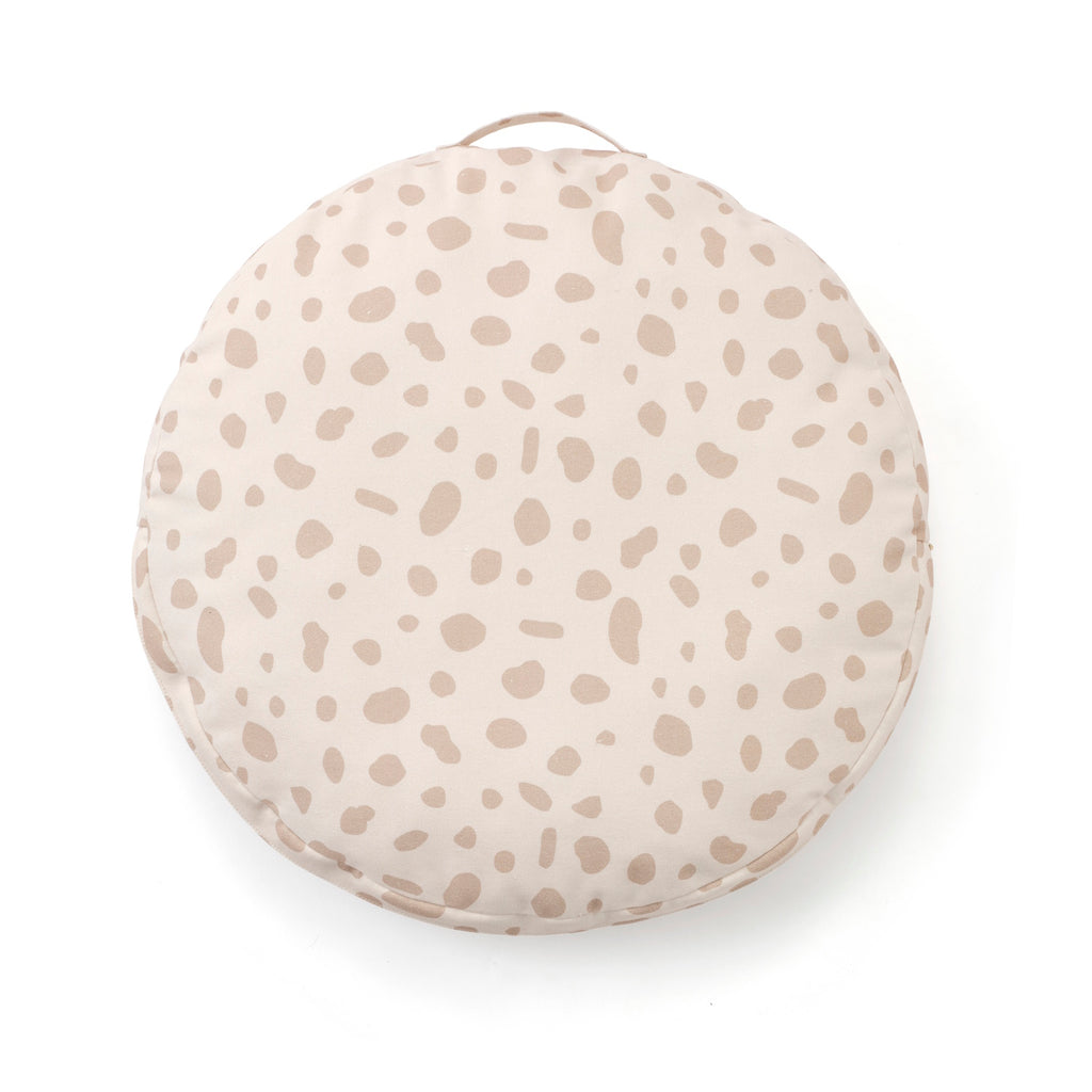 Round cushion with a light beige base and scattered taupe spots, resembling an abstract pattern. The soft tones convey a calming, cozy feel.
