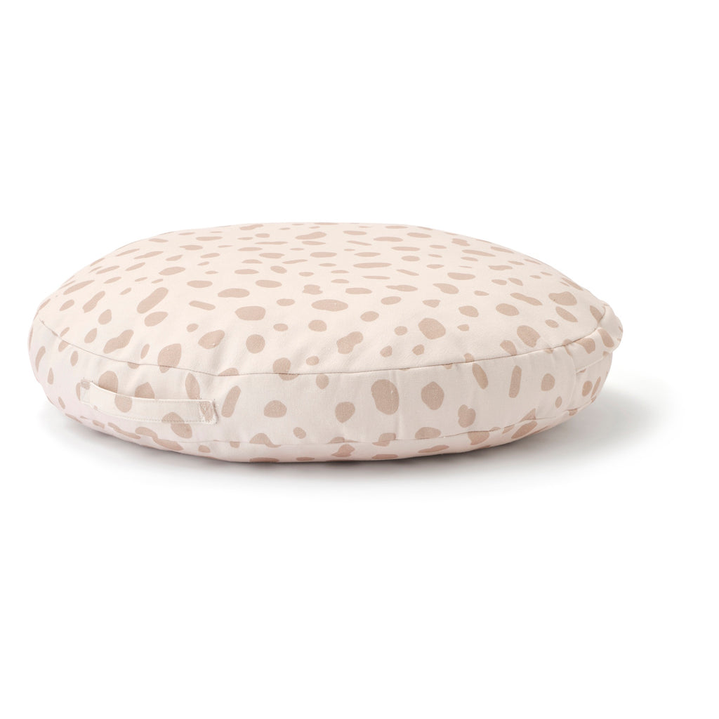 Round cushion with a light beige base and scattered taupe spots, resembling an abstract pattern. The soft tones convey a calming, cozy feel.