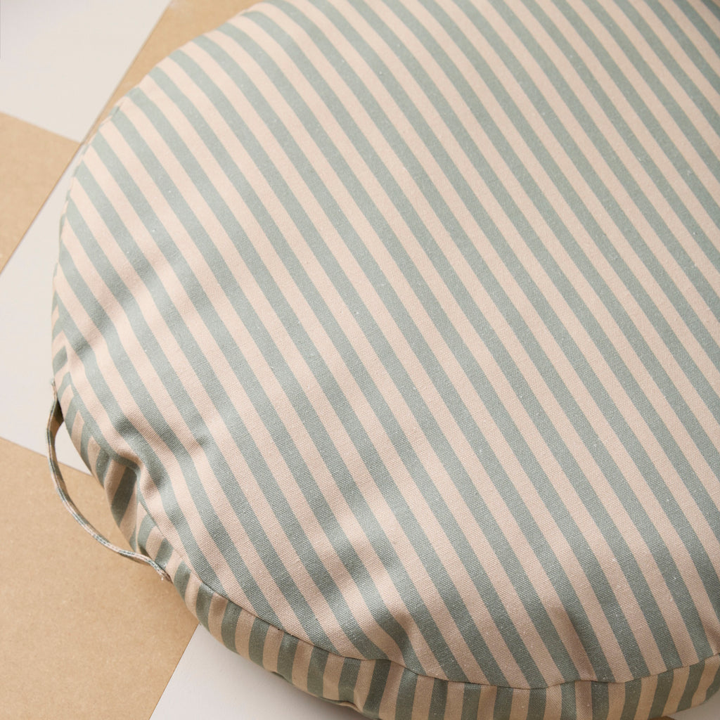 Round cushion with beige and gray horizontal stripes. The cushion has a calm, minimalist design, and includes a side handle.