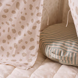 Round striped floor cushion with a side handle tucked inside a spotted play tent.