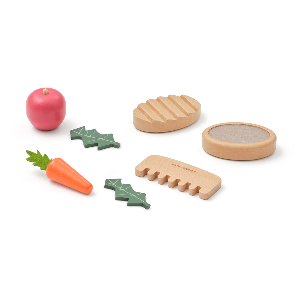 Toy kitchen set with wooden vegetables, bread, and accessories on a white background. Includes a red apple, carrot, and cutting board.