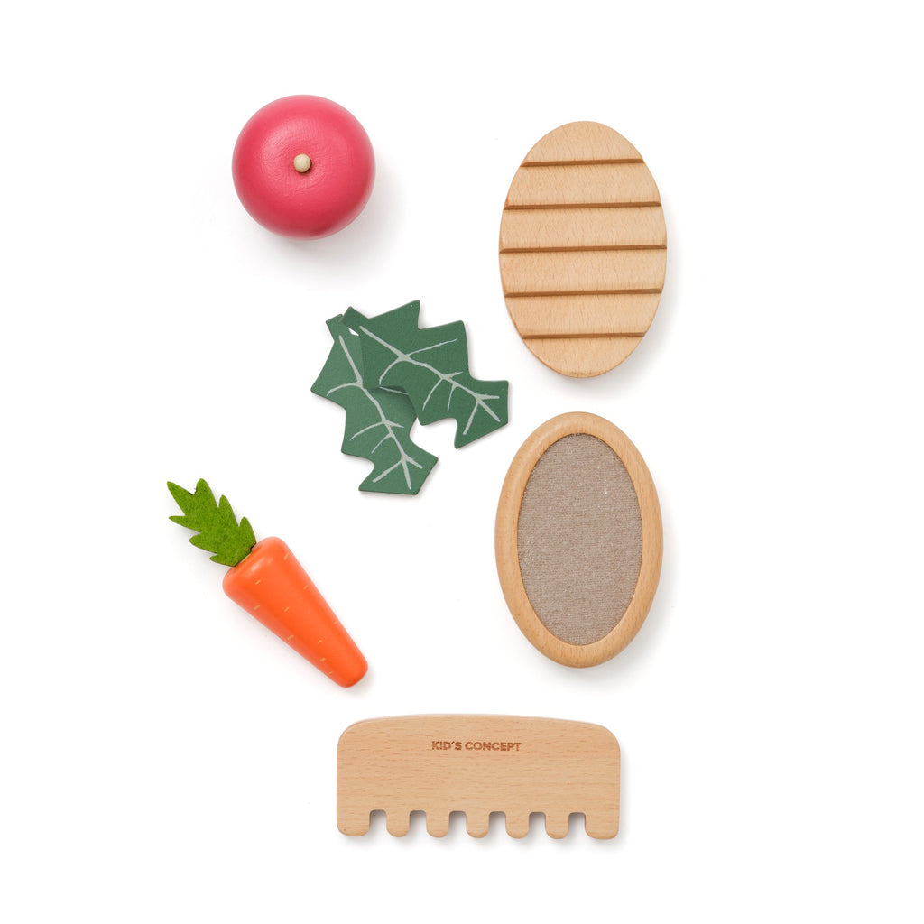 Toy kitchen set with wooden vegetables, bread, and accessories on a white background. Includes a red apple, carrot, and cutting board.