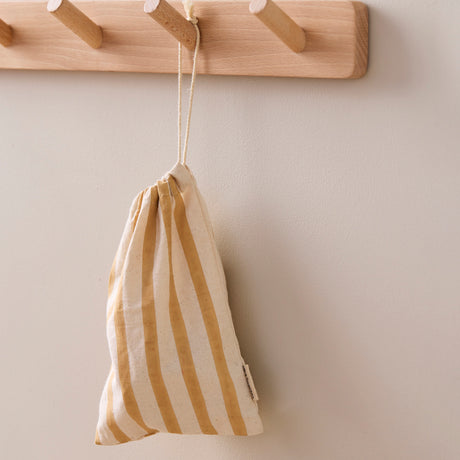 Yellow and cream striped drawstring cloth bag hanging on a wooden peg rack.