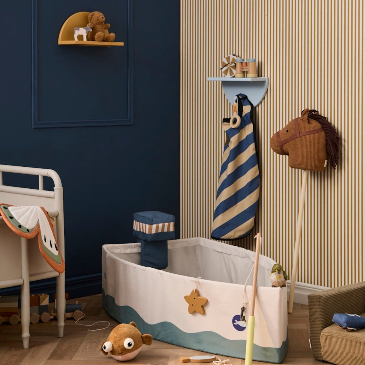 Plush brown hobby horse on a wooden stick in a child's bedroom with toys and a boat play set.